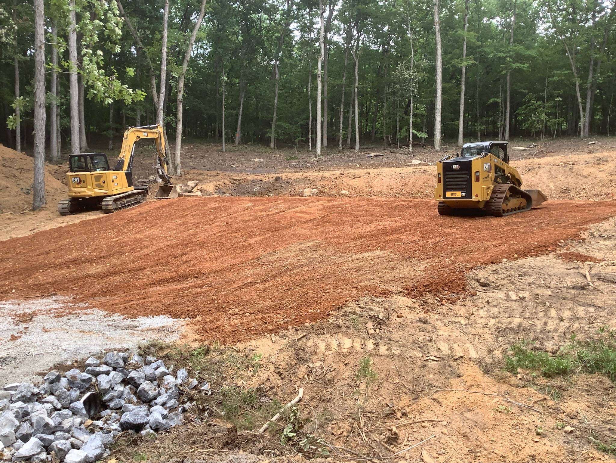 Excavator and track loader leveling a gravel pad