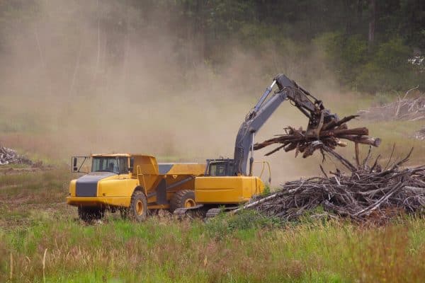 Excavator loading brush into an off-road haul truck